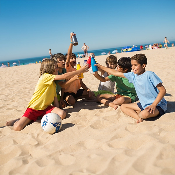 dzieci na plaży piją wodę